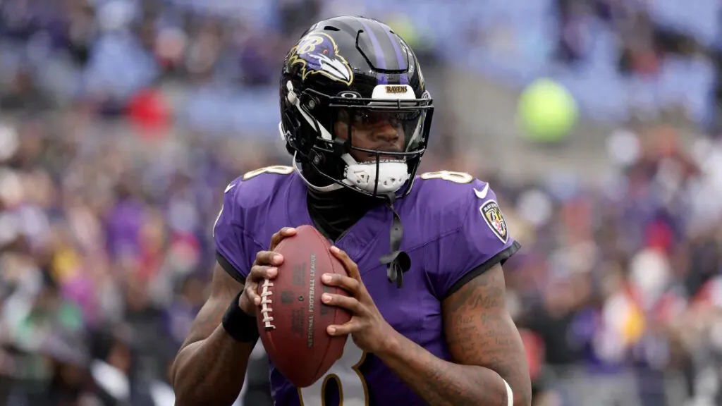 an African-American man stands in a football uniform with a ball in his hands